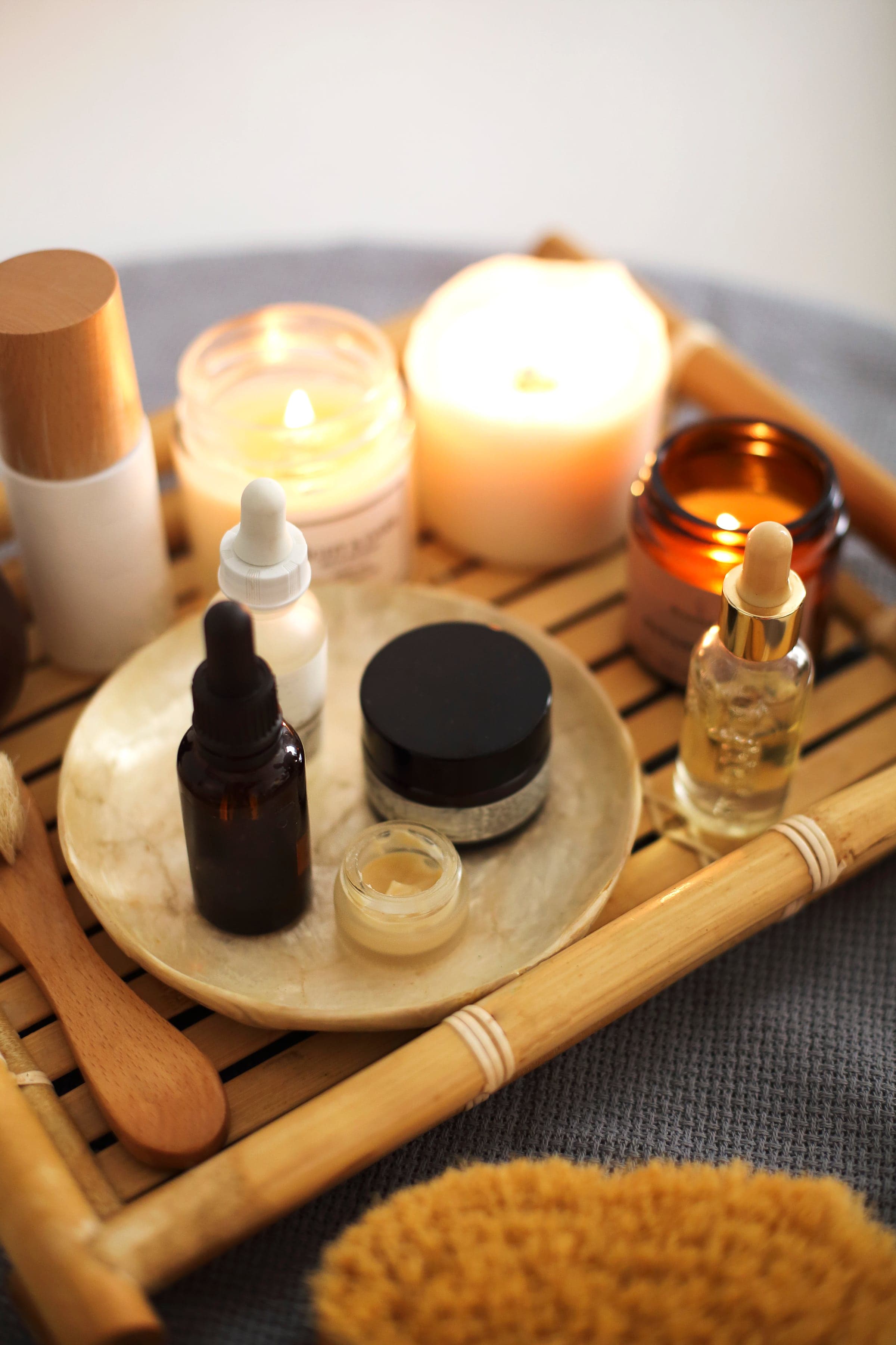 Massage oils in dark bottles on a tray by candlelight